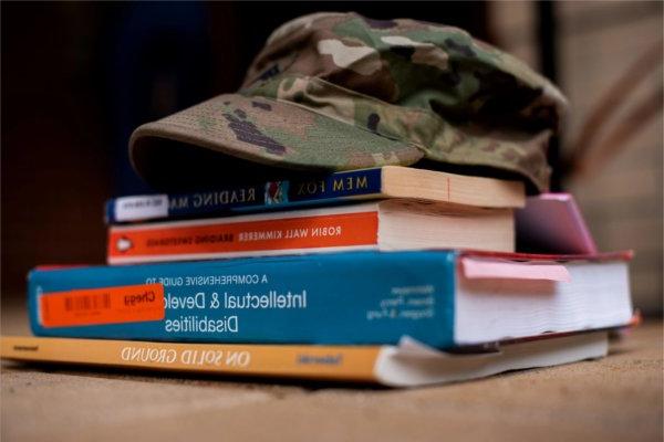 camouflage hat with brim atop a stack of books